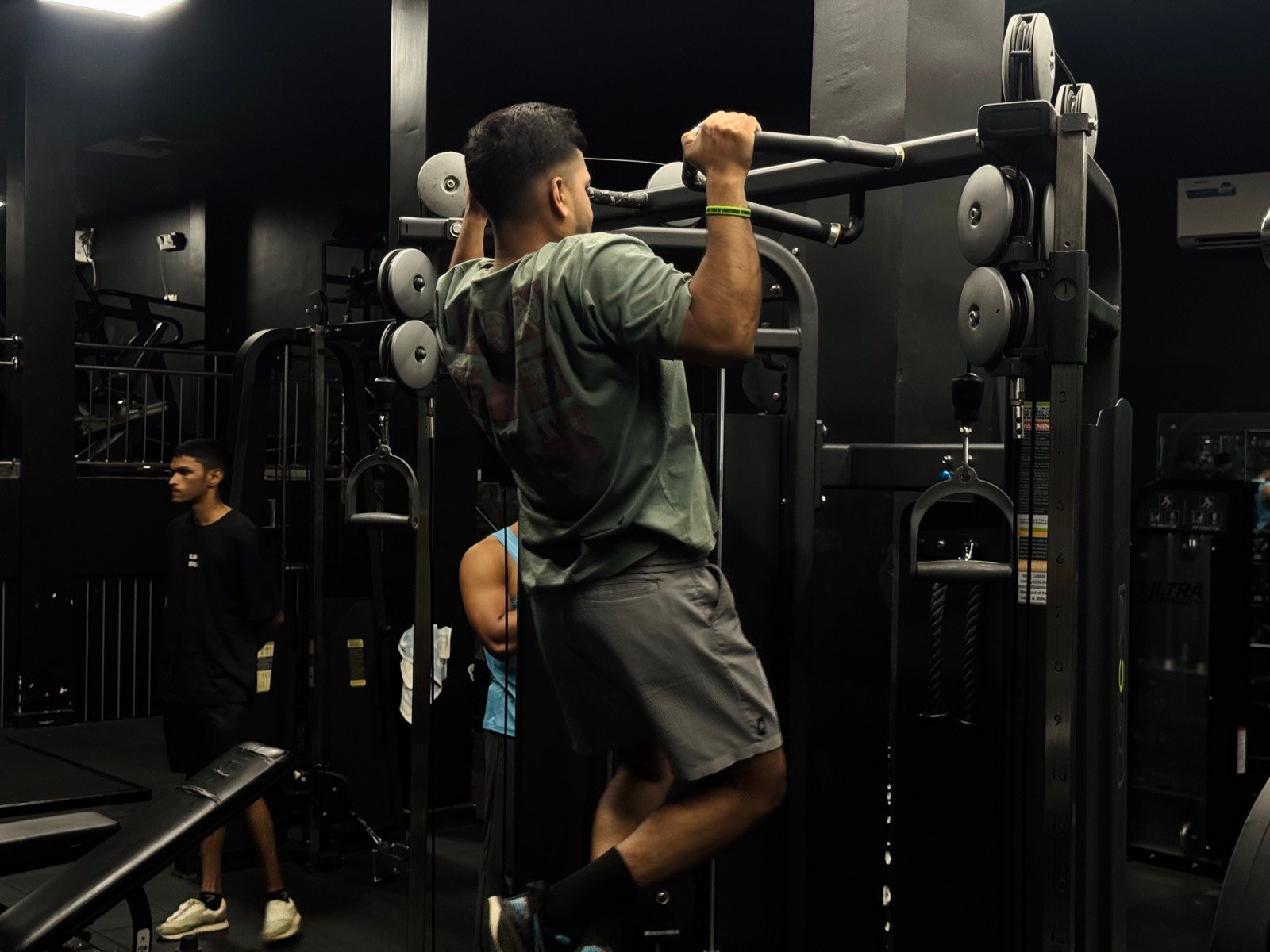 A member training on the assisted pull-up and dip station